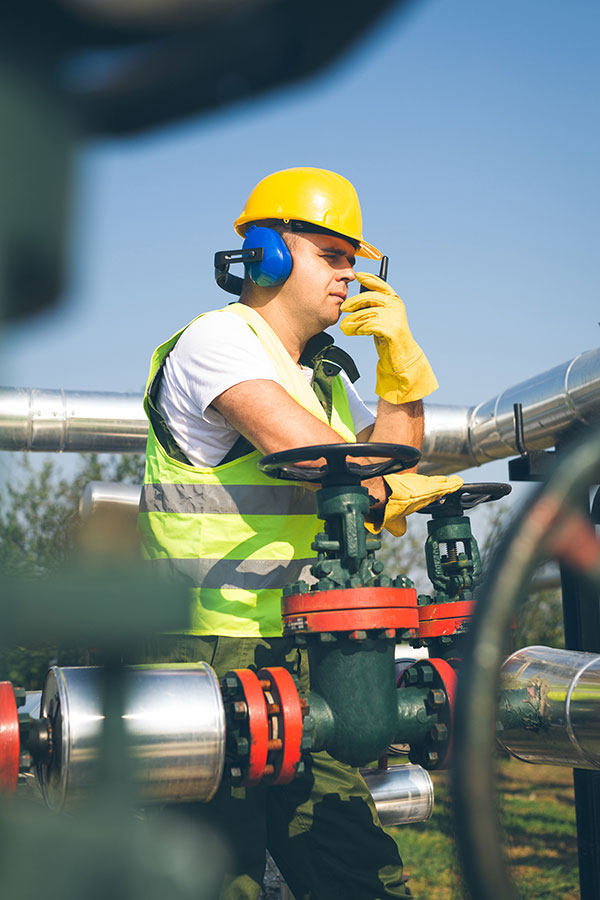 Man Wearing a Hard Hat and Safety Vest Using a Radio Man Wearing a Hard Hat and Safety Vest Using a Radio